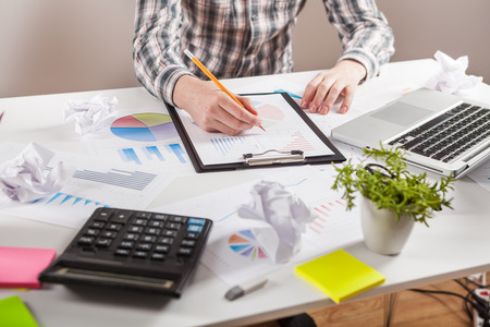 Businessman holding a pen is working with graph documents. Stock market chart and finger pointing on tablet in office.の写真素材