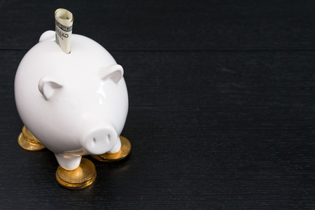 White piggy bank with one gold bitcoin coin new virtual money on a colored wooden backgroundの写真素材
