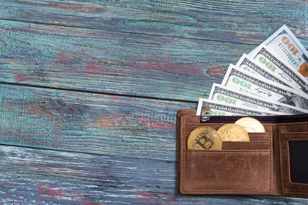Bitcoin and money in a purse on a colored wooden background. Bitcoin golden coin New virtual moneyの写真素材