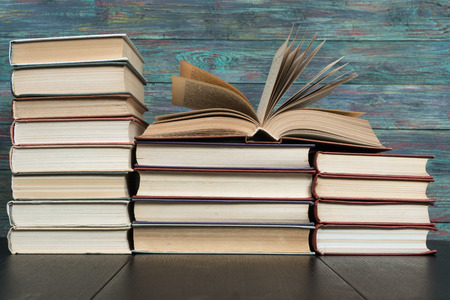 Open book hardback on Stack books on wooden background. Back to school with copy space.の写真素材