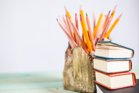 Set of pencils and pile of various books on wooden background. With copy space for your textの写真素材