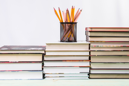 Set of pencils and pile of various books on wooden background. With copy space for your textの写真素材