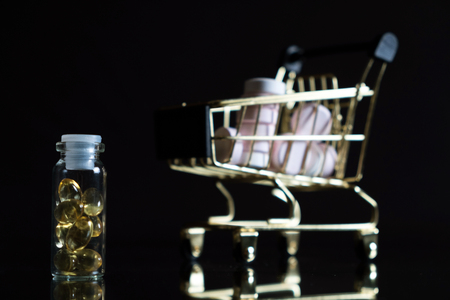 Medications and a gold shopping cart in the concept of expensive medicine. With copy space.の写真素材