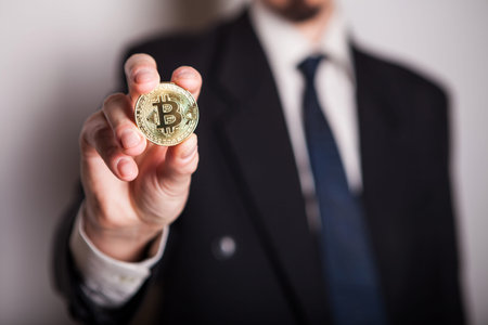 Golden Bitcoin in a man hand, Digitall symbol of a new virtual currency. Man recived money from...