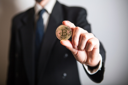 Golden Bitcoin in a man hand, Digitall symbol of a new virtual currency. Man recived money from bitcoin business.の写真素材