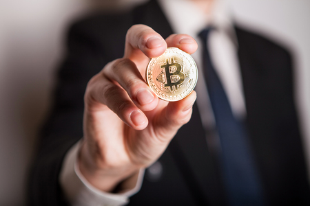 Golden Bitcoin in a man hand, Digitall symbol of a new virtual currency. Man recived money from bitcoin business.の写真素材