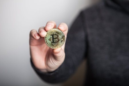 Golden Bitcoin in a woman hand, Digitall symbol of a new virtual currency. Woman recived money from...