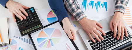 Business people discussing the charts and graphs showing the results of their successful teamwork.  Stock market chart and finger pointing on tablet in office.の写真素材