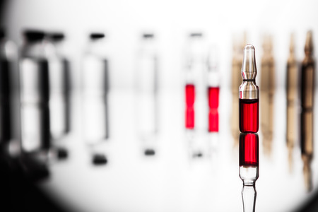 Ampoules with red liquid. On white background close up. Group of ampoules with a transparent medicine in medical laboratoryの写真素材