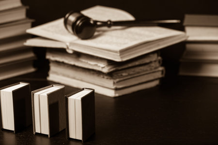 Judge gavel beside pile of books on black wooden background