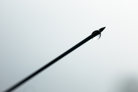 Close up Syringe needle medicine with liquid medicine drop against a background of medical bottles with injection, drug or vitaminの写真素材