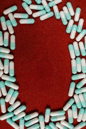 Assorted pharmaceutical medicine pills, tablets and capsules over red backgroundの写真素材