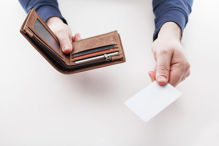 Men in suit with wallet and credit card. Selective focus of credit card in brown leather wallet.