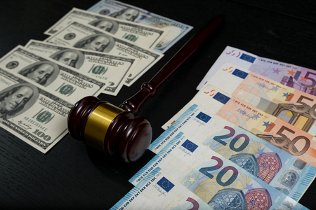Judge's gavel on the background of euro and dollar bills on wooden backgroundの写真素材
