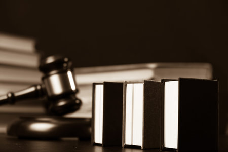 Judge gavel beside pile of books on black wooden background
