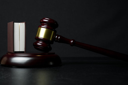 Judge gavel beside book on black wooden background