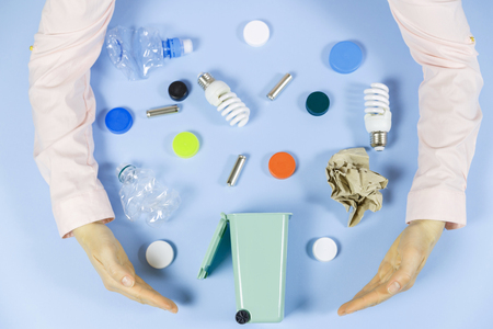 Women's hands sort the waste. Ecology concept, a lot of recyclable objects in containers on the color background. Copy space for your background.の写真素材