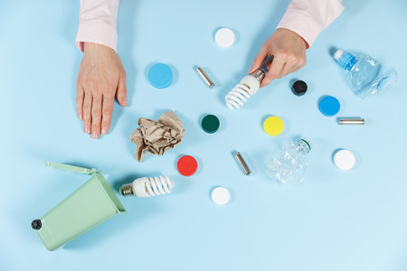 Women's hands sort the waste. Ecology concept, a lot of recyclable objects in containers on the color background. Copy space for your background.の写真素材