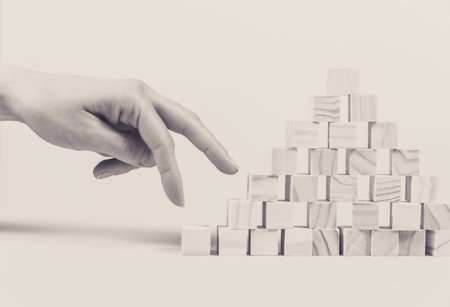 Closeup of businessman making a pyramid with empty wooden cubes. Concept of business hierarchy.