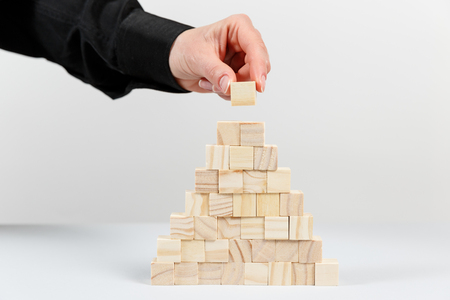 Closeup of businessman making a pyramid with empty wooden cubes. Concept of business hierarchy.の写真素材