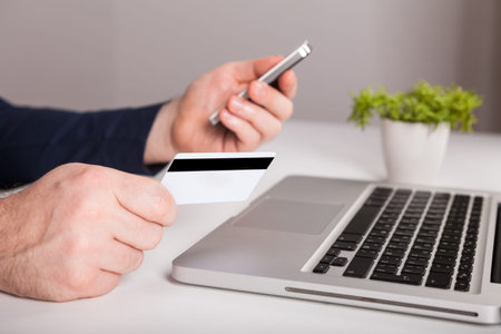 A man is going to pay for the goods in the internet using credit card and laptop computer. Online...