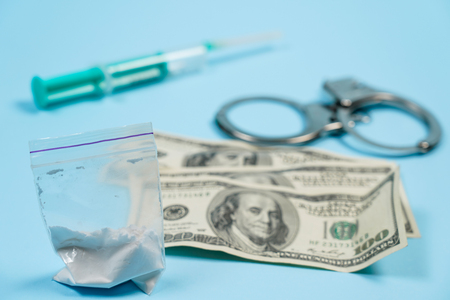 A bag of drugs, US dollars and handcuffs on the table. Concept - punishment for possession of narcotic drugs. Copy spase, spase for text.の写真素材