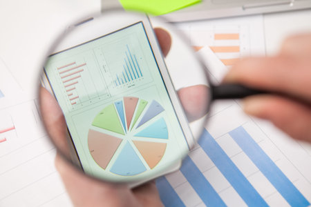 Businessman analyzing business graphs with magnifying glass. With copy space