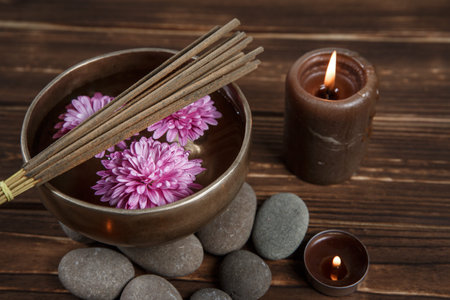 Singing bowl with candles with pebbles on dark wooden background with copy space.の写真素材