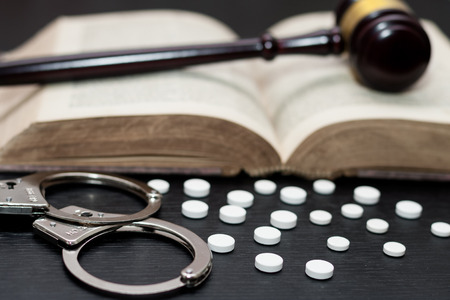 Judge's gavel with handcuffs, drugs on wooden table, drugs conceptの写真素材