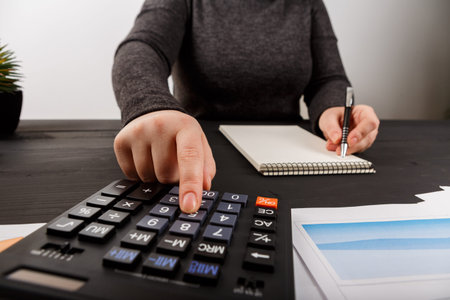 Close up of female accountant or banker making calculations. Savings, finances and economy concept