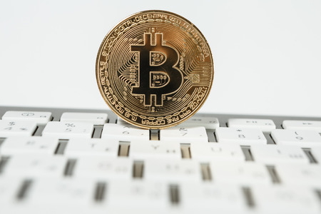 New virtual money Golden bitcoin coin on a white keyboard. Cryptocurrency. Business and Trading concept.の写真素材
