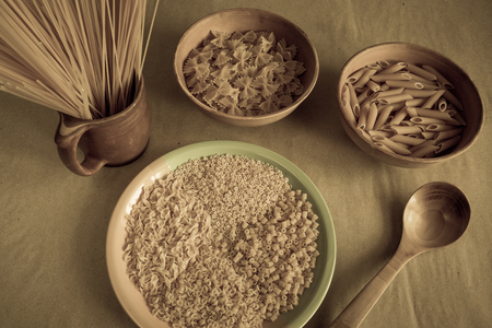 Composition of uncooked italian pasta. Pasta in a pottery. Spaghetti, farfalle, fusilli on gray background. Raw pasta background.の写真素材
