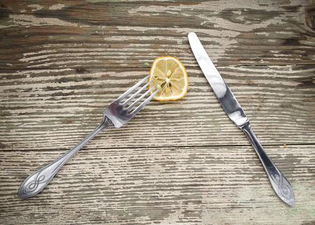 The dried lemon, knife and fork set on a wooden vintage tableの写真素材