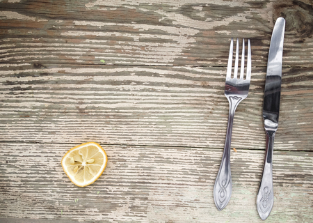 The dried lemon, knife and fork set on a wooden vintage tableの写真素材