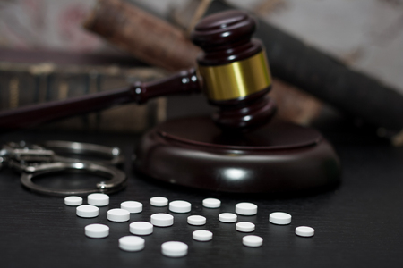 Judge's gavel with handcuffs, drugs on wooden table, drugs conceptの写真素材
