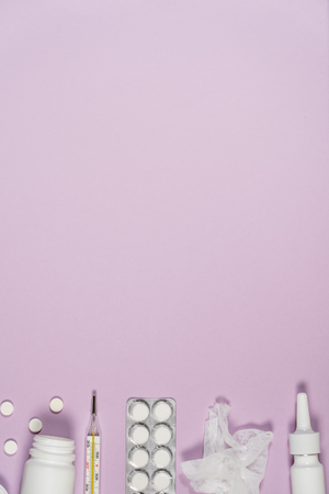 Treatment of colds and flu. Various medicines, a thermometer, sprays from a stuffy nose and a pain in a throat on a pink background. Copy space.の写真素材