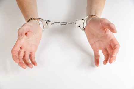 Womans hands in handcuffs. Isolated on white.の写真素材