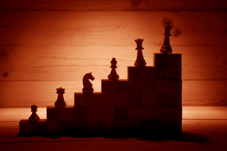 Business hierarchy. Strategy concept with chess pieces. Chess standing on a pyramid of wooden building blocks with the king at the top. copy space.の写真素材