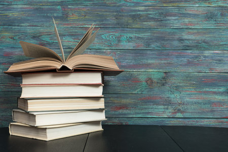 Open book hardback on Stack books on wooden background. Back to school with copy space.