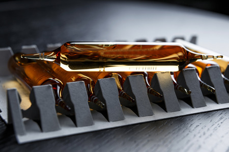 Horizontal perspective view of many brown ampoules set in pharmaceutical packaging white containerの写真素材