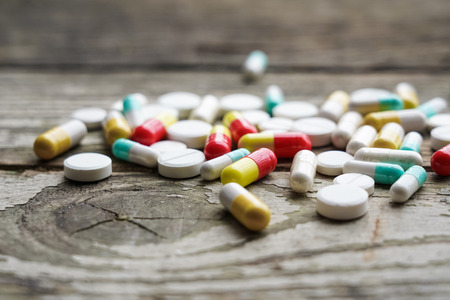 Selective focus on pill spread on wooden background. Global healthcare concept. Pharmaceutical industry. Drugs in medical container on wooden background.の写真素材