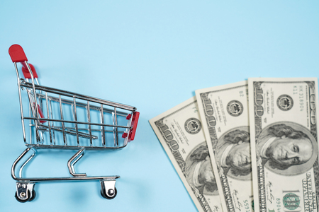 US dollars in shopping cart over blu background ,Dollar bill collect on shopping cart.Concept of money. Copy spase, spase for text.の写真素材