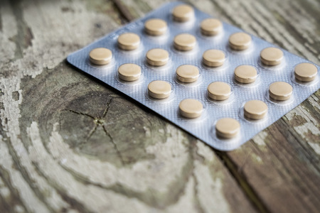 Medicine pills in packs.Pills in blister pack,Capsules and pill packed in blisters on white wooden background. scratched wooden tableの写真素材