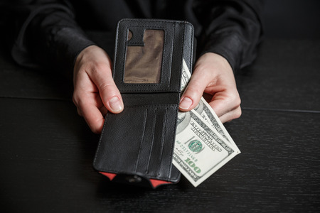 Businesswoman's hand in suit takes out dollar money from a wallet. Banknote One hundred dollar. The concept of finance. Close-up. Copy space. for your background.の写真素材