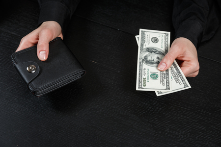 Businesswoman's hand in suit takes out dollar money from a wallet. Banknote One hundred dollar. The concept of finance. Close-up. Copy space. for your background.の写真素材