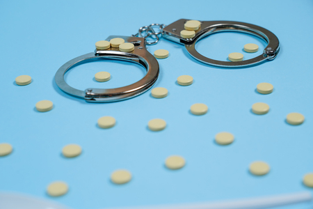 Pills on a blue background whith spoon and handcuffs. Copy spase, spase for text.の写真素材