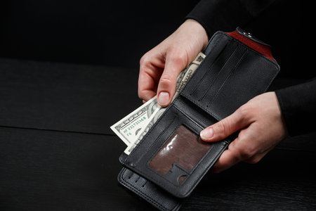 Businesswoman's hand in suit takes out dollar money from a wallet. Banknote One hundred dollar. The...