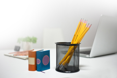 Photo of pencils in plastic glass, some pens and papers on the table in officeの写真素材