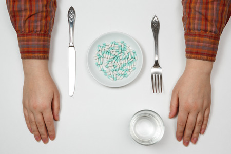 Supplementary food on the dish with fork and spoon on white tableの写真素材