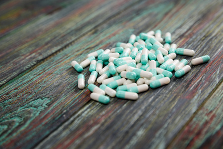 Blue and white capsules on a wooden background with copy space. Global healthcare concept. Pharmaceutical industry. Pharmacy.の写真素材